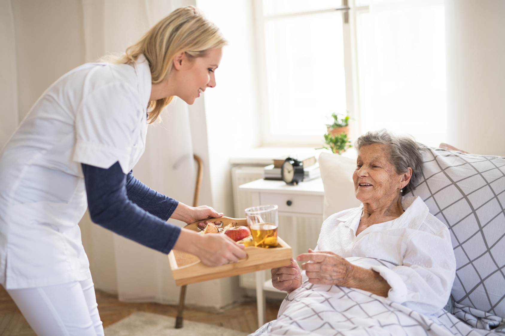 Professional caregiver providing gentle assistance to elderly resident with daily activities